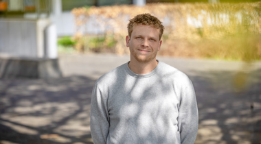 Collega Koen staat buiten het provinciehuis en heeft een grijze trui aan.