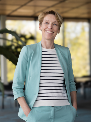De eerste afbeelding is een portret van collega Linda en de tweede afbeelding is een portret van collega Barbara. Zij zit op een zwarte stoel aan een bruine tafel.