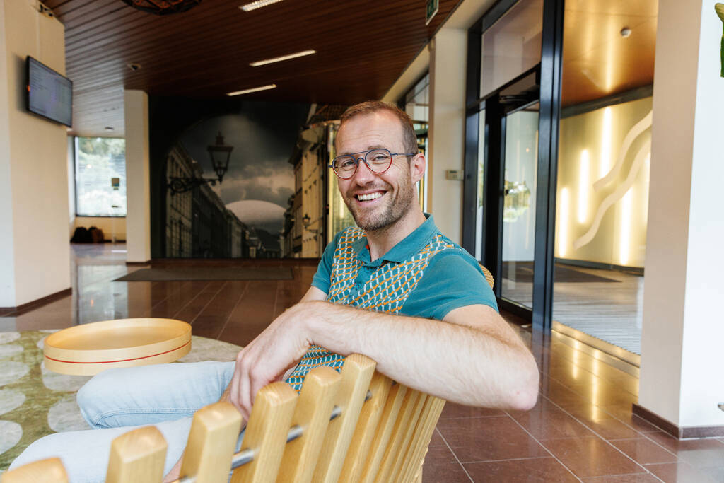 Collega Willem zit op een bank en kijkt naar de camera.