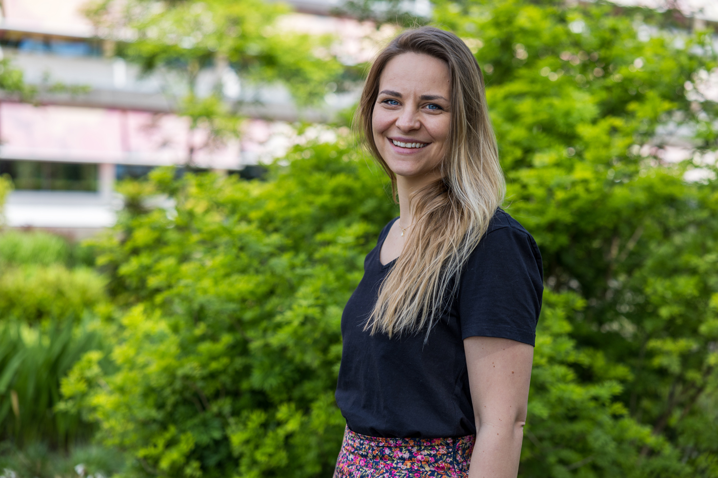 Collega Carola staat buiten het provinciehuis voor een grote groene struik.