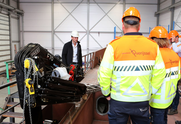 Op de eerste afbeelding is het werkbezoek te zien van de delegatie van de provincie Overijssel in Hendrik-Ido-Ambacht. Op de tweede afbeelding is één van de elektromotoren van het werkschip te zien.