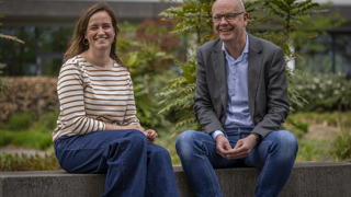 Floor en Sander zitten in de tuin van het provinciehuis op een stenenbank naast elkaar.