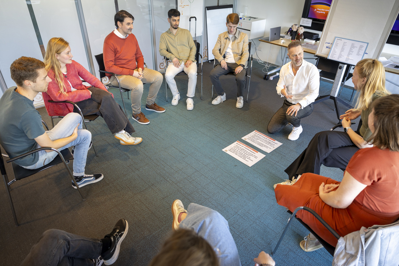 Trainees zitten in een kring en krijgen uitleg van een trainer.