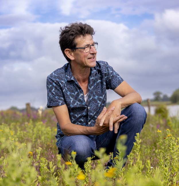 Collega Chris zit gehurkt tussen de natuur in het Vreugderijkerwaard.