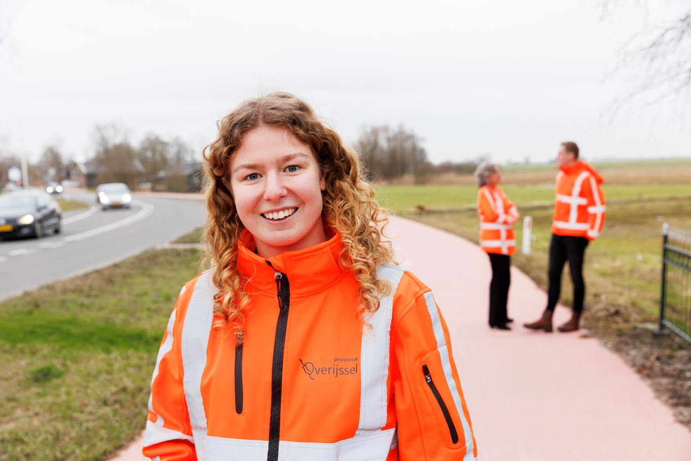 Op de voorgrond van de afbeelding staat collega Maud, op de achtergrond zijn collega's Eiberlien en Tiemen te zien die in gesprek zijn met elkaar.