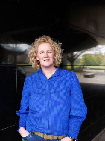 Portretfoto van Natasja de tegen een zwarte muur geleund staat en ze draagt een blauwe blouse en de tweede afbeelding is een sfeerbeeld van de kantine van het provinciehuis