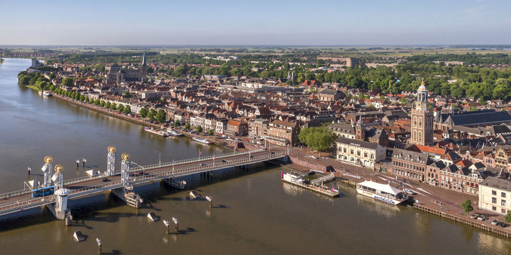 Het stadsaanzicht van Kampen is te zien. Water op de voorgrond en de stad op de achtergrond.