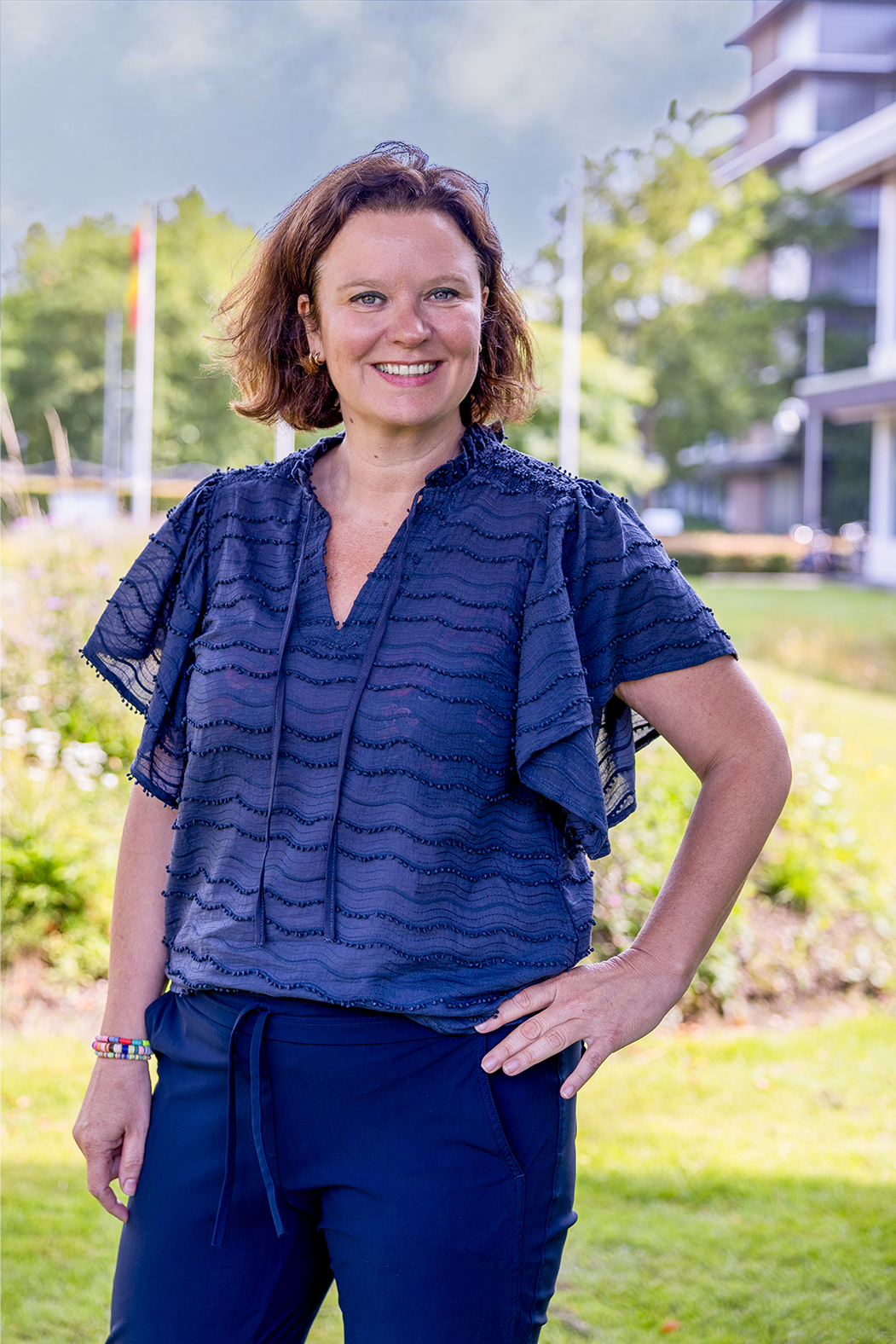 Collega Jessica staat in de tuin voor het provinciehuis. Je ziet haar van voren staan.