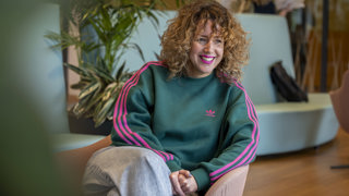Collega Manon zit glimlachend op een roze stoel in het provinciehuis.