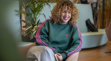 Collega Manon zit glimlachend op een roze stoel in het provinciehuis.