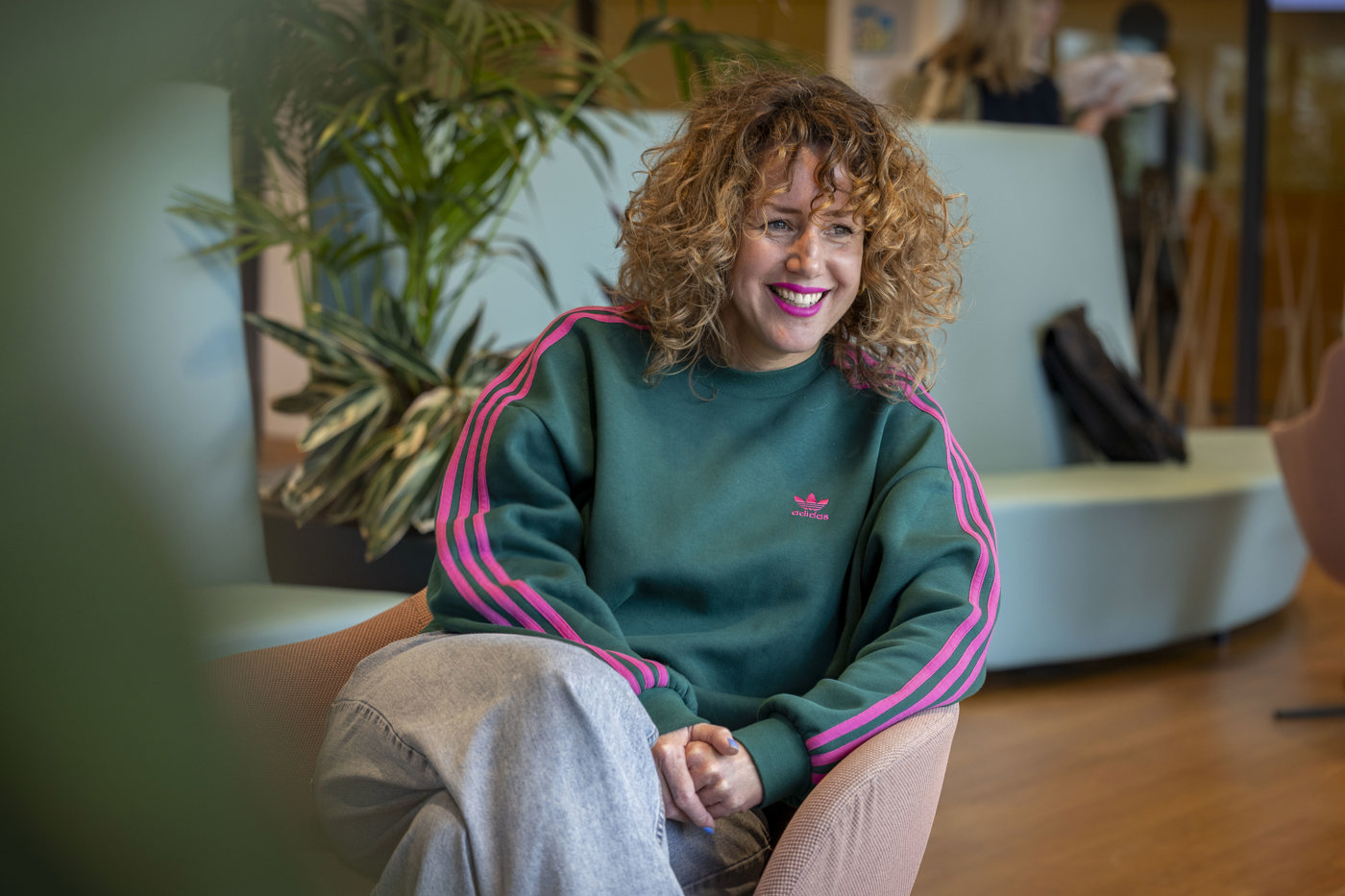 Collega Manon zit glimlachend op een roze stoel in het provinciehuis.
