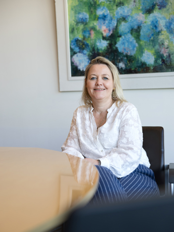 De eerste afbeelding is een portret van collega Linda en de tweede afbeelding is een portret van collega Barbara. Zij zit op een zwarte stoel aan een bruine tafel.
